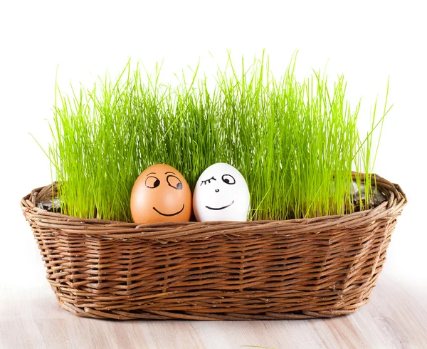 Dos huevos sonrientes divertidos en cesta con hierba. baño de sol . —  Fotos de Stock