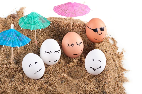 Великодні кумедні яйця під парасолькою на піску — стокове фото