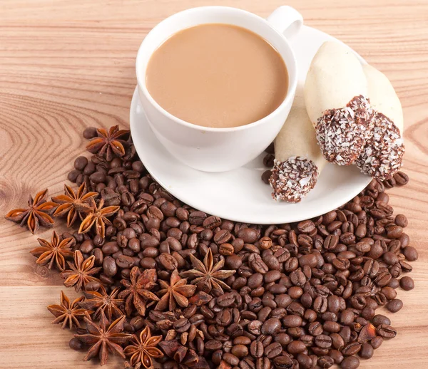 Coffee cup, anise on coffee beans, sweets on the wooden background — Stock Photo, Image