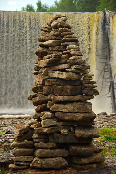 Пирамида камней на фоне водопада — стоковое фото