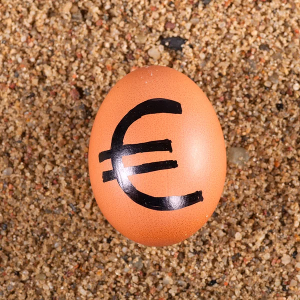 Afbeelding van grote witte ei met euro ondertekenen op een zand — Stockfoto