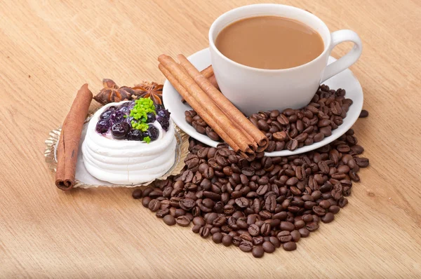 Coffee cup with coffee beans ans sweet cake on a wooden background — Stock Photo, Image