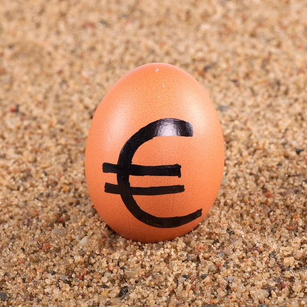 Afbeelding van grote witte ei met euro ondertekenen op een zand — Stockfoto