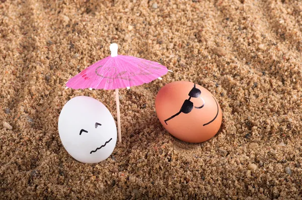 Ovos engraçados de Páscoa abaixo do guarda-chuva em uma areia — Fotografia de Stock