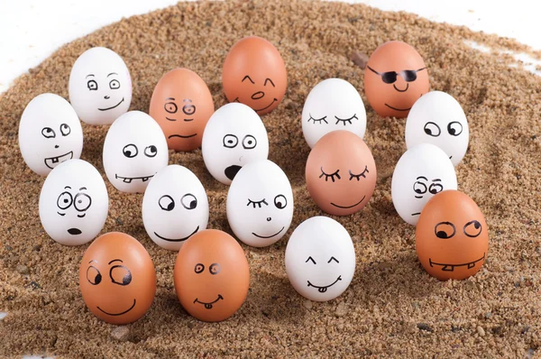 Group of Funny crazy smiling eggs on a sand — Stock Photo, Image