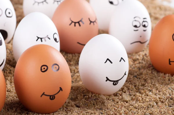 Group of Funny crazy smiling eggs on a sand — Stock Photo, Image