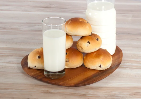 Grupo de bollos cruzados calientes y leche en una tabla de madera —  Fotos de Stock