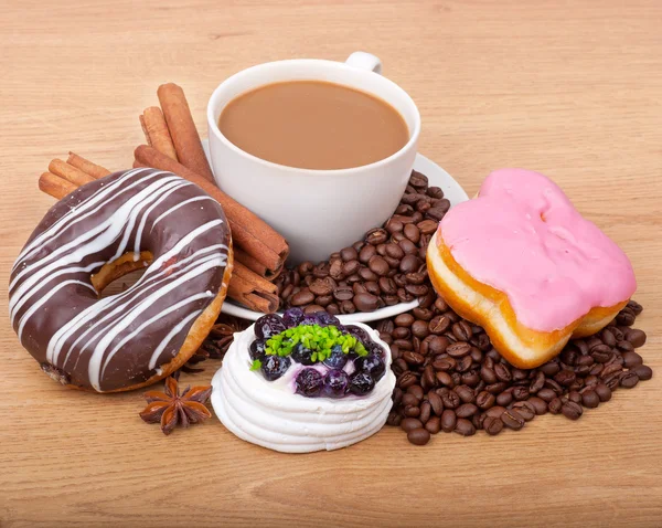 Coffee cup with coffee beans ans sweet cake on a wooden background — Stock Photo, Image