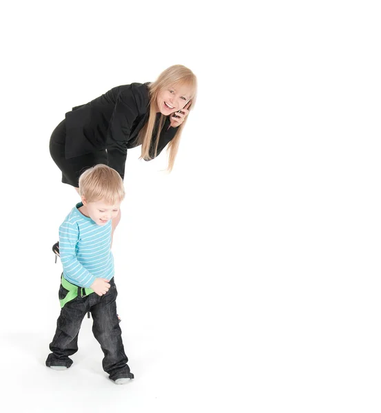 Young business woman speaking by phone and her son over white background — Stock Photo, Image