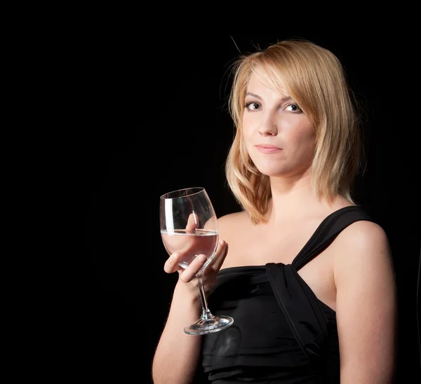 Woman in black dress with glass over dark background — ストック写真