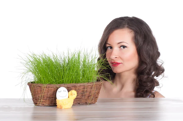 Красивая женщина с пасхальной корзиной с зеленой травой, курицей и улыбающимся яйцом — стоковое фото