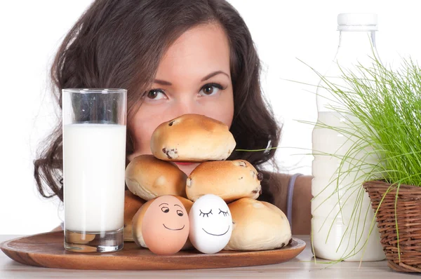 Mooie vrouw met melk, broodje en Pasen mandje van gras — Stockfoto