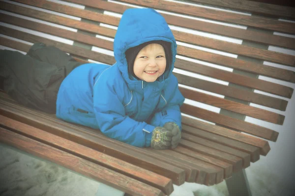 Child on the bench in winter time — Stock Photo, Image