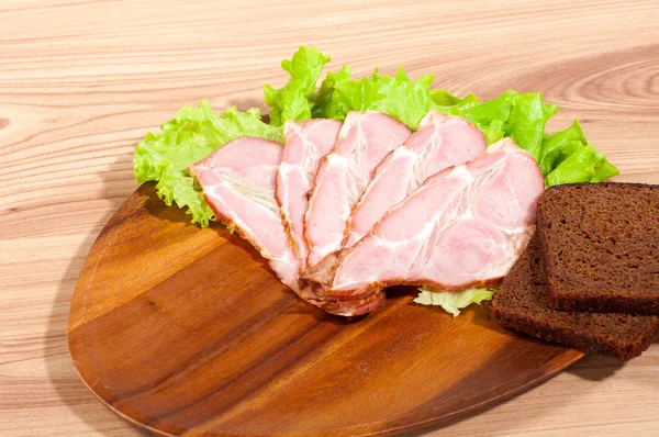 Ham and lettuce with piece of bread on a wooden plate — Stock Photo, Image