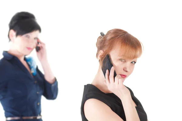 Dos mujeres hablando por teléfonos celulares y sonriendo — Foto de Stock