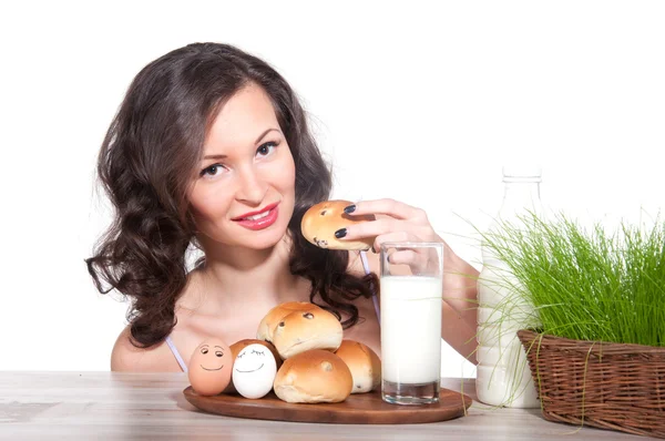 Mooie vrouw met melk, broodje en Pasen mandje van gras — Stockfoto