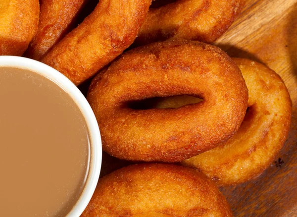 Coffee cup and oil donuts on a wooden plate — Stock Photo, Image