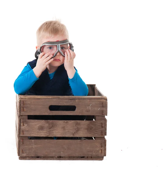 Kleine jongen met pilot bril in houten kist — Stockfoto