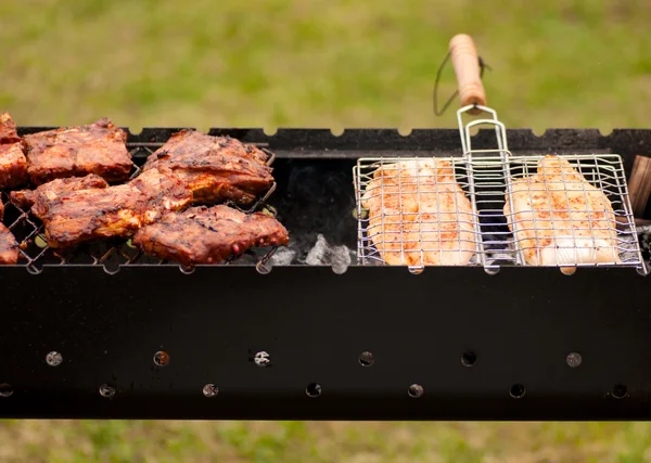 Grillrippchen und Fisch auf dem Grill mit Holzkohle — Stockfoto