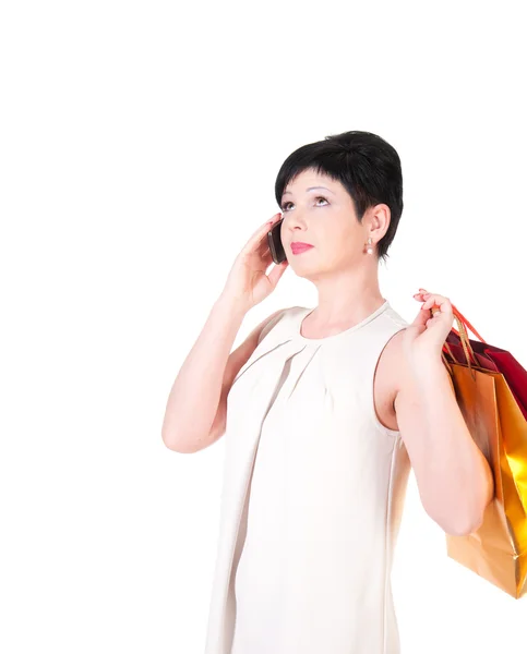 Mujer morena en vestido crema con bolsas de compras posando —  Fotos de Stock