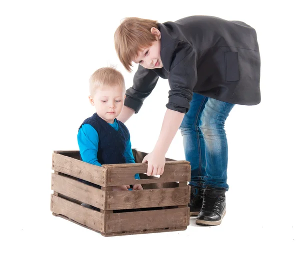 Kleiner Junge in Holzkiste und alter Bruder daneben — Stockfoto