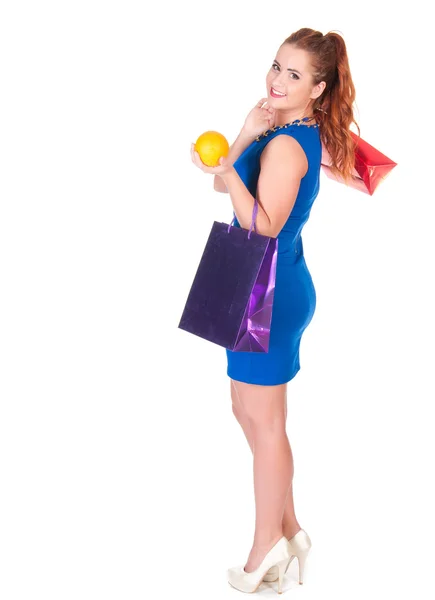 Mujer joven en vestido azul con bolsas de compras y naranja —  Fotos de Stock