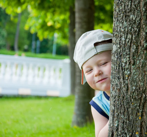 Petit garçon caché derrière un arbre — Photo