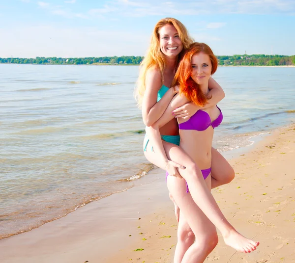 Zwei schöne junge Frauen spielen an einem Strand — Stockfoto