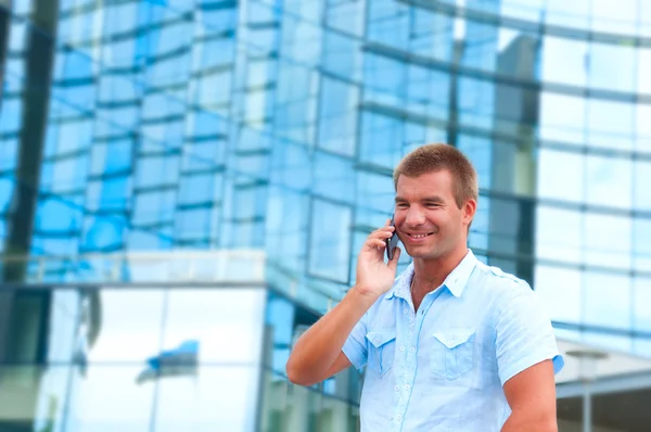 Homem de negócios falando ao telefone na frente do edifício de negócios moderno — Fotografia de Stock