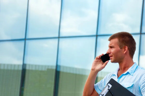 Iş adamı ile defter ve modern işletme binası önünde hareket eden telefon — Stok fotoğraf