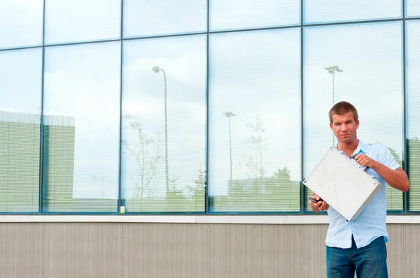 Business man with metal case in front of modern business building — Stock Photo, Image