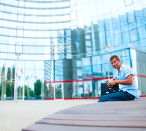 Hombre de negocioscon portátil frente al moderno edificio de negocios — Foto de Stock