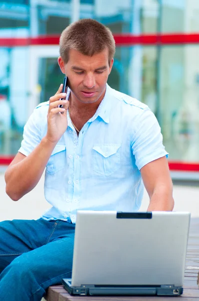 현대적인 비즈니스 건물 앞의 laptopand 휴대 전화와 함께 비즈니스 남자 — 스톡 사진