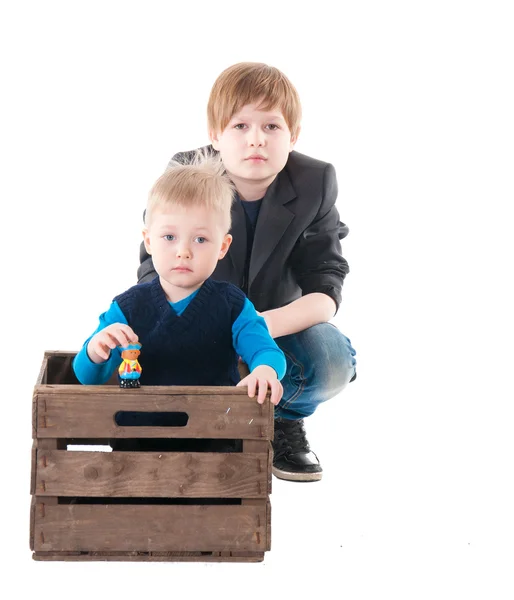 Little boy in wooden box and old brother beside — Stock Photo, Image