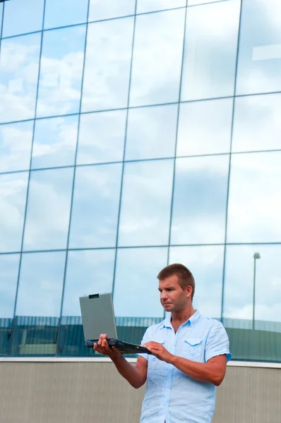 Business manwith laptop in front of modern business building — Stock Photo, Image