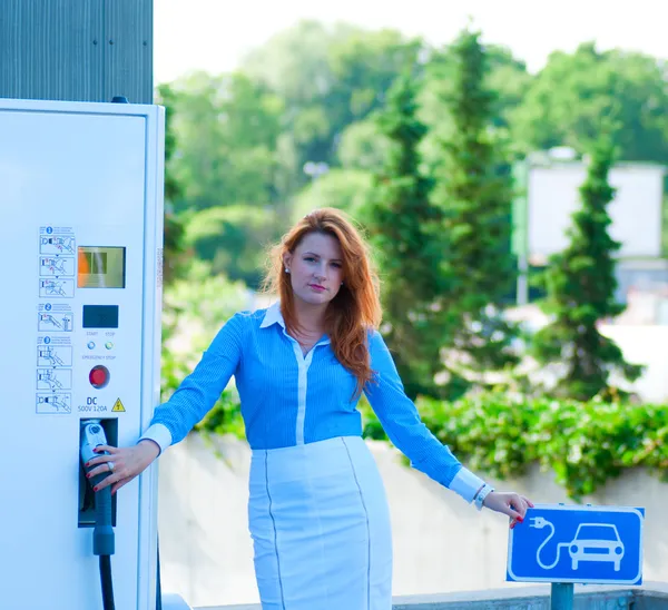 Woman with the power supply for Charging of an electric car — Stock Photo, Image