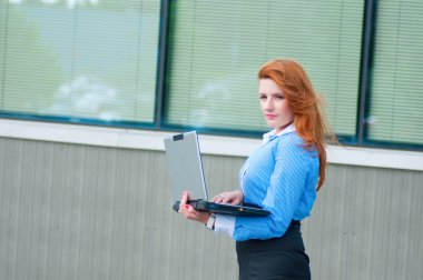 iş kadını ile bir dizüstü bilgisayar ofis binası önünde poz