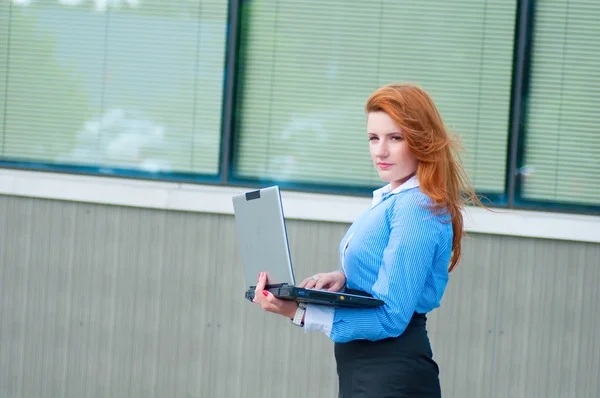 Business woman posing with a laptop in a front of office building — Stock Photo, Image