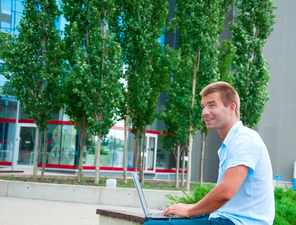 Homem de negócios com laptop na frente do edifício de negócios moderno — Fotografia de Stock