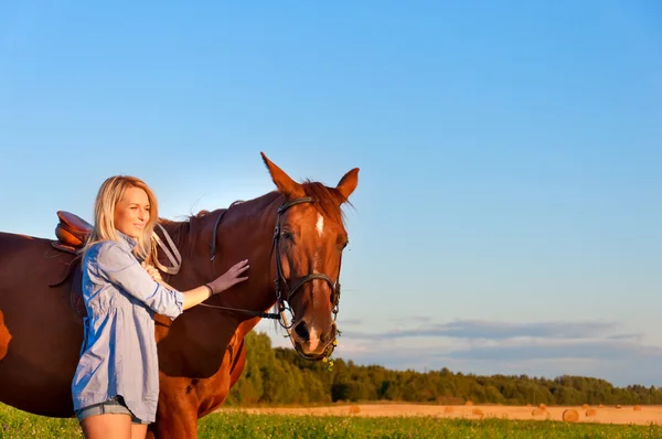 Chica joven caminando con un caballo en el campo — Foto de Stock