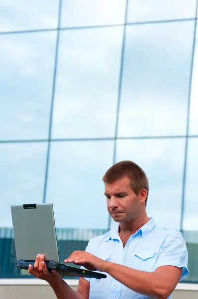 Geschäftsmann mit Laptop vor modernem Geschäftshaus — Stockfoto