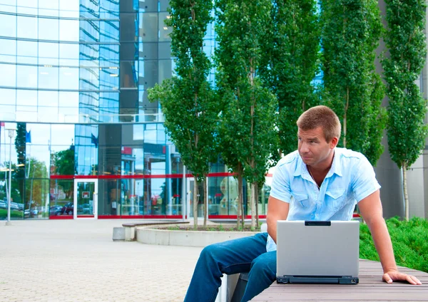 Homem de negócios com laptop na frente do edifício de negócios moderno — Fotografia de Stock