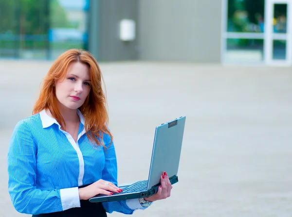 商务女人摆在前面的办公大楼中的一台笔记本电脑 — 图库照片
