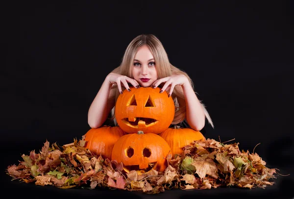 Charmante halloween heks met grappige pompoenen en bladeren — Stockfoto