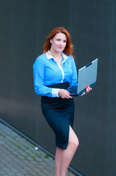 Mujer de negocios posando con un portátil en un frente del edificio de oficinas —  Fotos de Stock