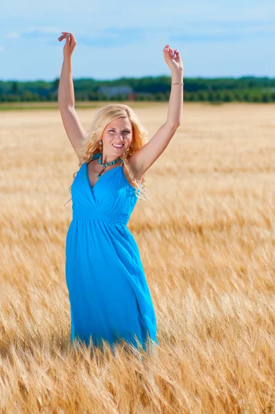 Счастливое женское голубое платье в золотой пшенице — стоковое фото