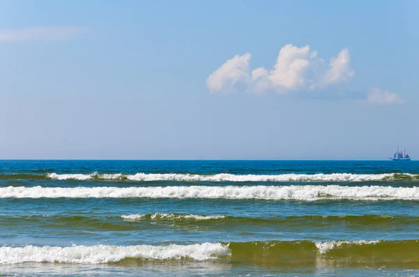 Mar y olas y barco solitario sobre el cielo azul — Foto de Stock