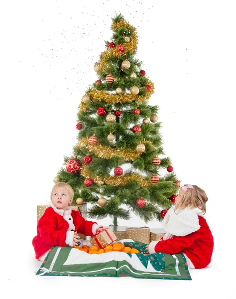 Duas crianças brincando sob a árvore de Natal — Fotografia de Stock