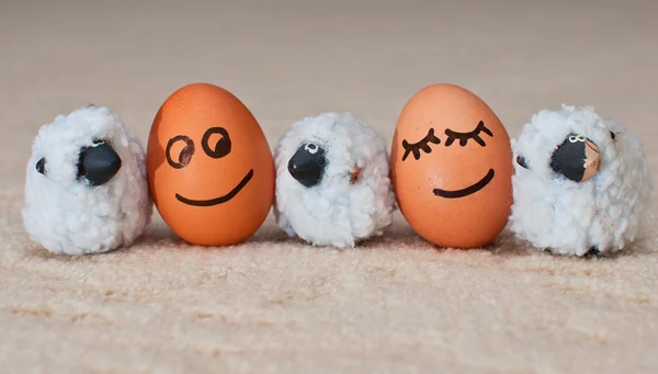 Two funny smiling eggs near a small sheeps — Stock Photo, Image