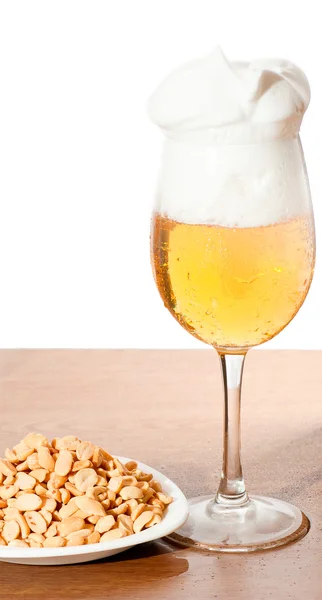 冷たいビールとナッツ木製の表面の上のガラス — ストック写真